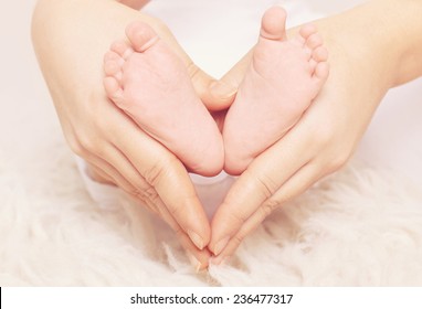 Close Up Of Baby Feet In Heart Shaped In Hands 