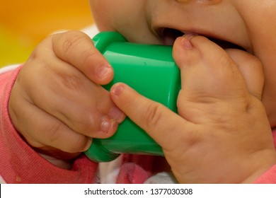 Close Up Of Baby Girl Hands, With Syndactyly, Playing With Green Toy. Medical Condition, Webbed Fingers