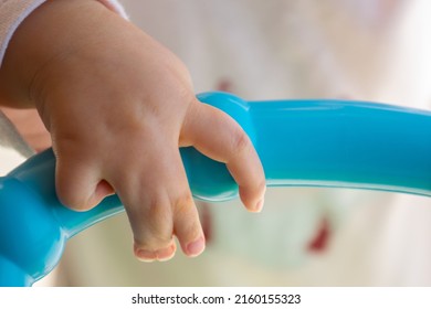 Close Up Of Baby Girl Hands, With Syndactyly, Playing With Green Toy. Medical Condition, Webbed Fingers