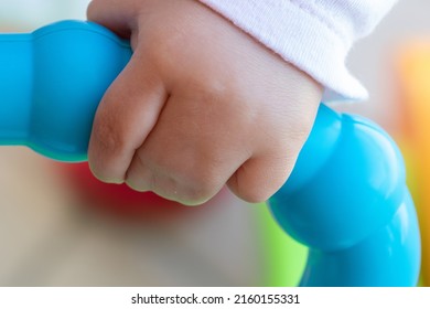 Close Up Of Baby Girl Hands, With Syndactyly, Playing With Green Toy. Medical Condition, Webbed Fingers