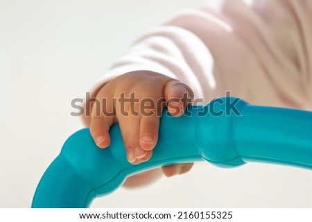 Close up of baby girl hands, with syndactyly, playing with green toy. medical condition, Webbed fingers