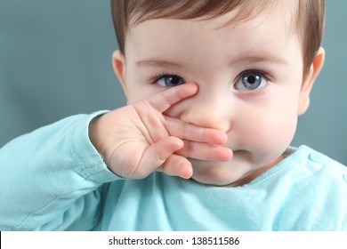 Close Up Of A Baby Girl Looking At Camera With A Big Blue Eyes With A Green Unfocused Background