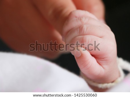 Close up baby holding mother finger 