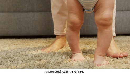 Close Up Of Baby's Feets Making His First Steps With Mom On The Carpet And Coming Closer To The Camera At Home. Inside