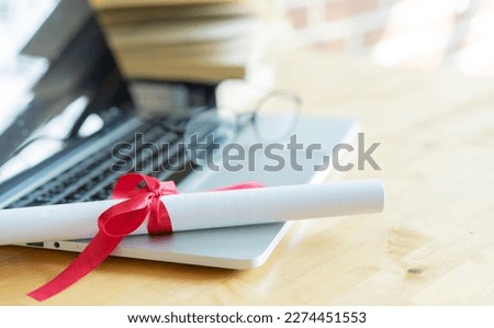 close up bachelor's degree certificate on laptop with book in the library for online learning graduation concept