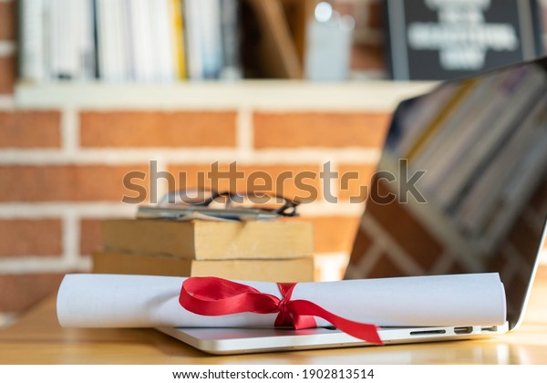 close up\
bachelor\'s degree certificate on laptop with book in the library\
for online learning graduation\
concept	