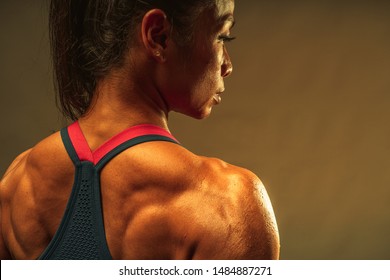 Close Up Of Back Muscle Of The Asian Athletic Middle Age 40 Year Old Woman Show The Lean And Healthy Muscle Body After The Fitness Training On The Warm Light Background.