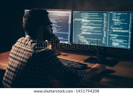 Close up back rear behind photo stubble handsome he him his guy pensive hands arms chin coder code development outsource IT processing two monitors table office wear specs formalwear plaid shirt