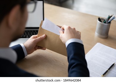 Close up back rear shoulder view focused young male ceo executive manager sitting at workplace table, opening envelope with business correspondence, banking notification or financial documents. - Shutterstock ID 1849642084