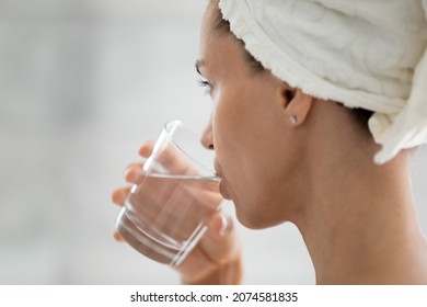Close up back side view happy peaceful young hispanic woman drinking glass of fresh filtered mineral pure water after morning shower, enjoying daily healthcare habit, sipping aqua, stay hydrated.