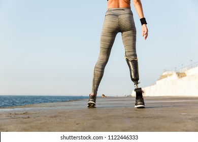 Close up back view of disabled athlete woman with prosthetic leg standing at the beach - Powered by Shutterstock