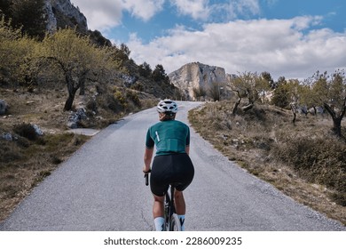 Close up back view of a female cyclist during ride.Woman cyclist wearing cycling kit and helmet riding on gravel bike.Cycling through stunning Spanish mountain landscapes. - Shutterstock ID 2286009235