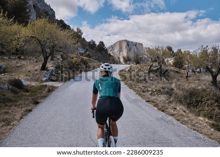 Close up back view of a female cyclist during ride.Woman cyclist wearing cycling kit and helmet riding on gravel bike.Cycling through stunning Spanish mountain landscapes.