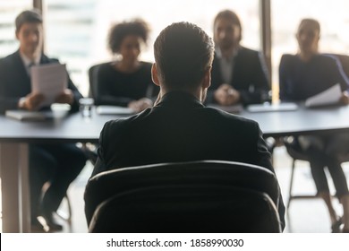Close up back view of male job candidate apply have interview with employers at office meeting. Man intern or applicant speak on work recruitment talk with company recruiters team. Employment concept. - Shutterstock ID 1858990030