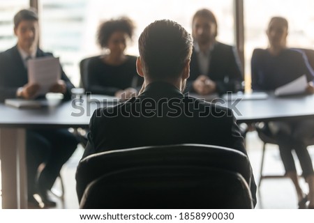 Close up back view of male job candidate apply have interview with employers at office meeting. Man intern or applicant speak on work recruitment talk with company recruiters team. Employment concept.