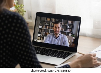 Close up back view of woman  look at laptop screen talk on video call with male teacher or trainer, woman student have online distant webcam conversation or virtual conference with man coach or tutor