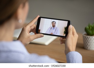 Close up back view of woman talk speak on video call on smartphone with male doctor or therapist. Female have online digital consultation on cellphone with GP. Technology, virtual event concept. - Powered by Shutterstock