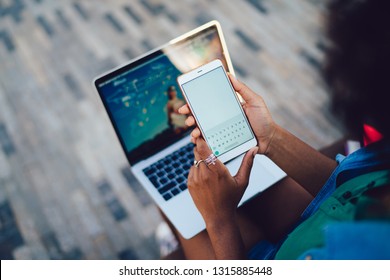 Close Up Back View Of Woman Using Cellphone With Copy Space And Basic Text Message Digital Keyboard On Screen. Female Hands With Mobile Phone Front Open Laptop Computer On Knees. Waiting Notification