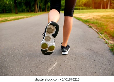 Close Up From The Back Of A Young Blonde Woman Running Away From The Camera On The Road In A Park
