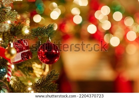Close up background image of single red ornament on Christmas tree with twinkling lights, copy space