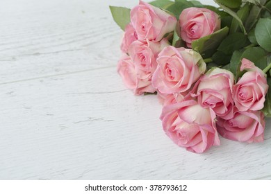 Close up background with pink roses over white wooden table. Top view with copy space