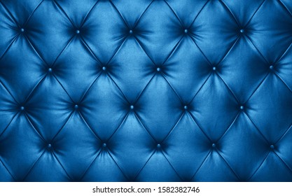 Close up background texture of dark blue capitone genuine leather, classic retro Chesterfield style soft tufted furniture upholstery with deep diamond pattern and buttons