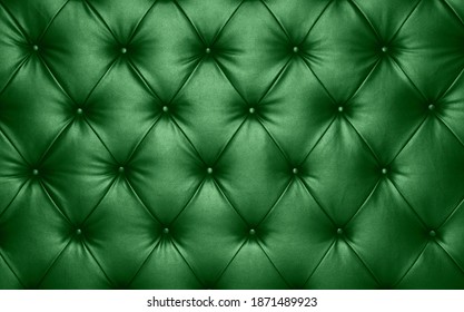 Close up background texture of dark green capitone genuine leather, retro Chesterfield style soft tufted furniture upholstery with deep diamond pattern and buttons