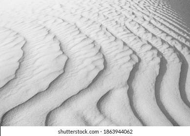 Close up of background texture of desert sand dunes. Beautiful structures of sandy dunes on sunny summer day. Annual growth of area of sand with wave from wind in desert for holiday vacation concept