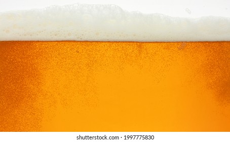 Close Up Background Texture Of Lager Beer With Bubbles And Froth, Pouring In Glass, Low Angle, Side View