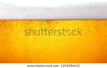 Close up background texture of lager beer with bubbles and froth in glass, low angle side view