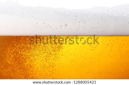 Close up background texture of lager beer with bubbles and froth in glass, low angle side view