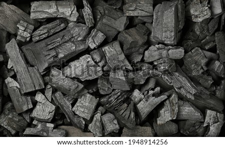 Close up background texture of many black lump charcoal pieces ready for barbecue grill, elevated top view, directly above