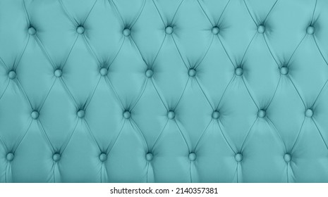 Close up background texture of pastel blue capitone genuine leather, retro Chesterfield style soft tufted furniture upholstery with deep diamond pattern and buttons