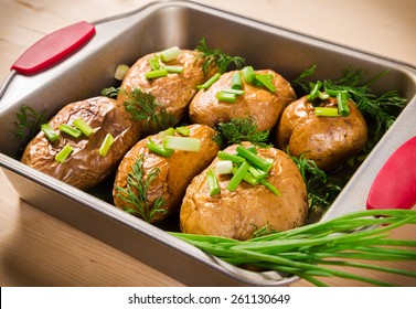 close up of baked potatoes with green onion in oven tray