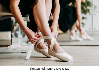 Close up for ballet dancer putting on, tying ballet shoes. Ballerina putting on her pointe shoes. - Powered by Shutterstock