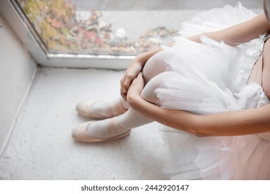 Close up ballet pointe shoes. Ballerina dancer sits by the window, pose relaxed, with pointe shoes on and the soft tulle of tutu, evoking moment of tranquility. - Powered by Shutterstock