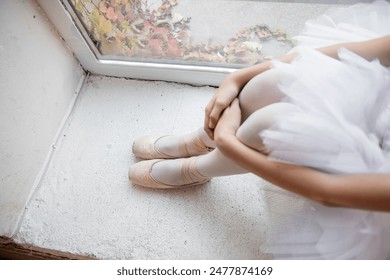 Close up ballet pointe shoes. Ballerina dancer sits by the window, pose relaxed, with pointe shoes on and the soft tulle of tutu, evoking moment of tranquility. - Powered by Shutterstock