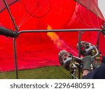 Close up of balloonist, gas burner, fire flame. Inflation hot air balloon. Basket lying on its side. Ventilator and coils, part of a serie.