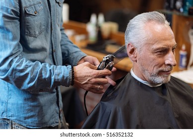 Close Up Barber Trimming Hair Of Old Man