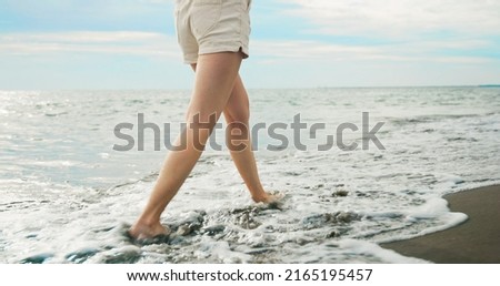 close up bare feet of asian woman wearing in shorts is walking at beach
