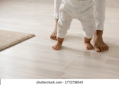 Close Up Barefoot African American Woman With Toddler Child Standing On Warm Wooden Floor With Underfloor Heating, Caring Loving Young Mum Teaching Adorable Little Daughter To Walk At Home