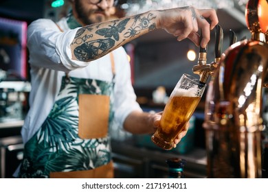 Close up of barista pouring draft beer at bar counter while working in a pub. - Powered by Shutterstock