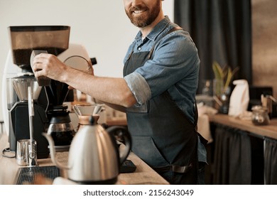 Close up of Barista pours coffee beans into coffee machine tank for grinding standing behind counter