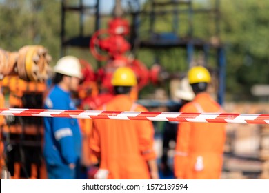 Close up at barricade line which is use to isolate dangerous working area for safety reason with blurred background of working people are conduct safety meeting together.
