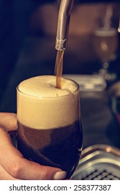 Close Up Of Bartender Hands Pouring Dark Beer Into Glass