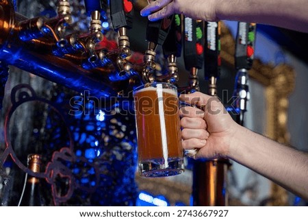 Close up of bartender pouring draft beer from tap.