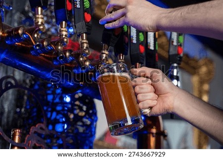 Close up of bartender pouring draft beer from tap.
