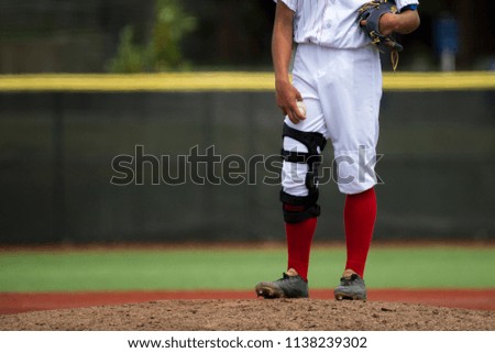close up of baseball players legs with red stockings standing on first base