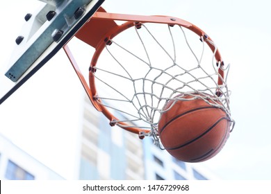 Close up of basketball shooting through hoop against urban background, copy space - Powered by Shutterstock