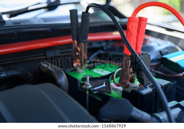 Close up battery jumper cables connect to car\
battery for charging dead\
battery